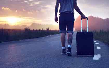 A photo of a man in the road with his luggage
